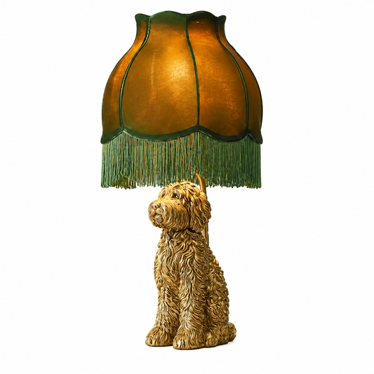 A decorative table lamp featuring a sculpted golden-brown dog base and a matching fringed shade in warm amber and green tones, shown on a plain white background.